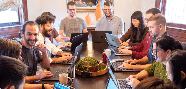 Coverbase team collaborating at a table with laptops