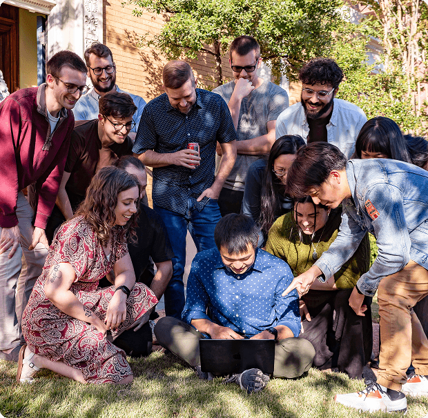 Coverbase team gathered outdoors reviewing work on a laptop